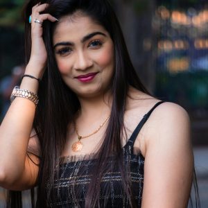 Smiling woman with long hair and striking accessories in an urban outdoor setting.