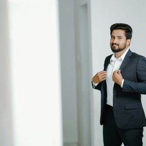 A confident man in a gray suit standing indoors, showcasing fashion and style.
