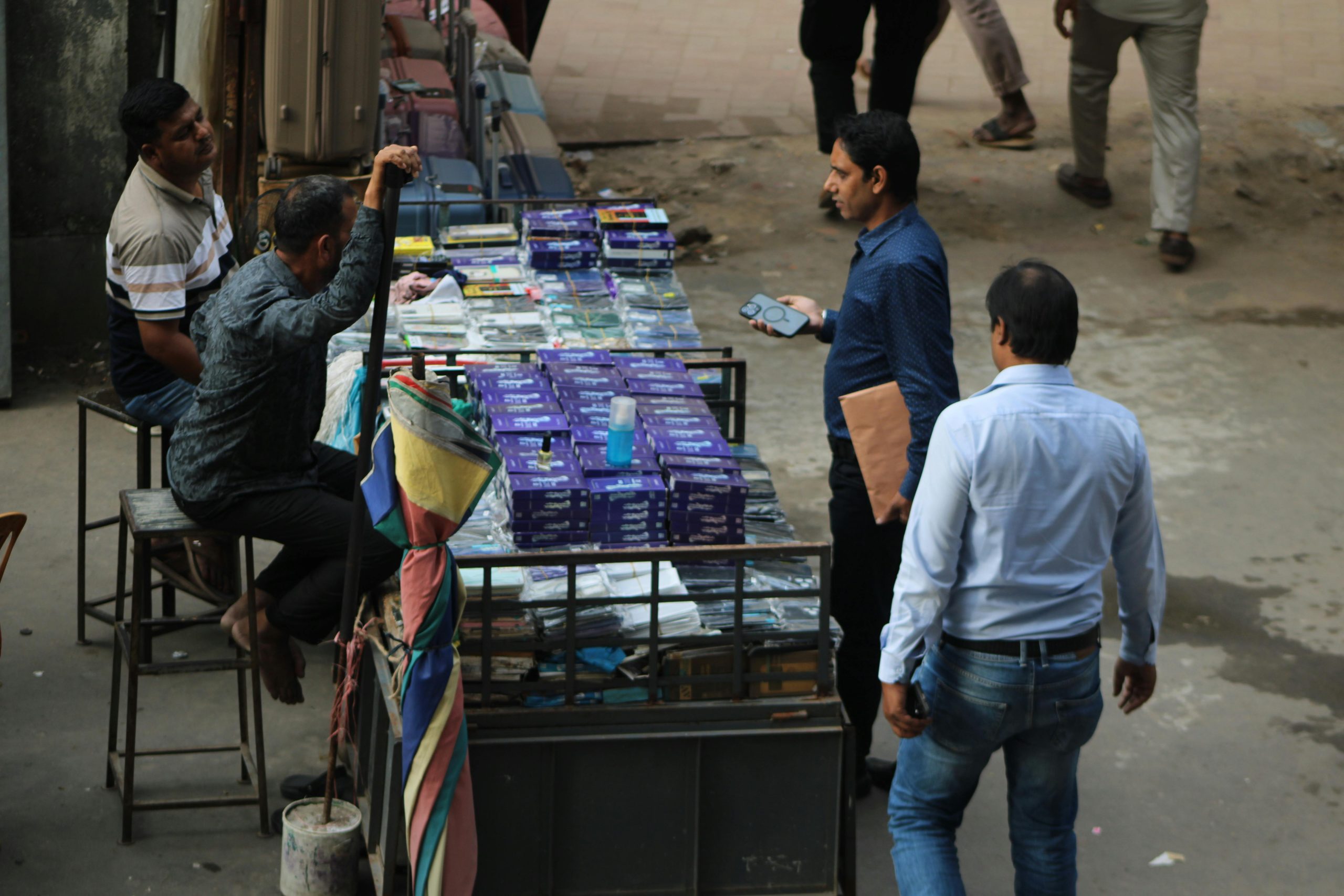 Men browsing mobile accessories at a street market stall.